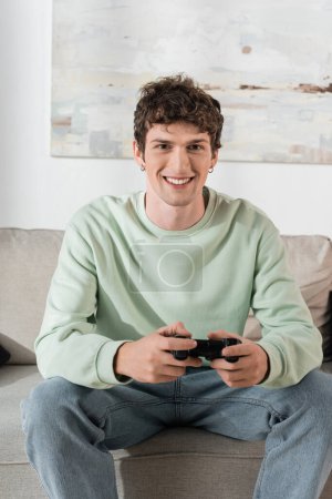 Photo for KYIV, UKRAINE - OCTOBER 24, 2022: cheerful young man in sweatshirt playing video game - Royalty Free Image