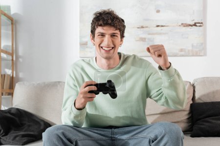 Photo for KYIV, UKRAINE - OCTOBER 24, 2022: excited young man in sweatshirt playing video game - Royalty Free Image