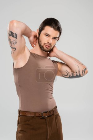 Foto de Muscular tattooed man in tank top posing isolated on grey - Imagen libre de derechos