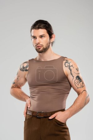 Photo for Stylish and tattooed man posing with hand in pocket isolated on grey - Royalty Free Image