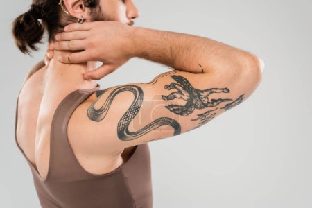 Foto de Cropped view of muscular man in tank top touching neck isolated on grey - Imagen libre de derechos