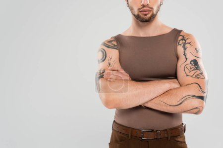 Cropped view of bearded tattooed man crossing arms isolated on grey 
