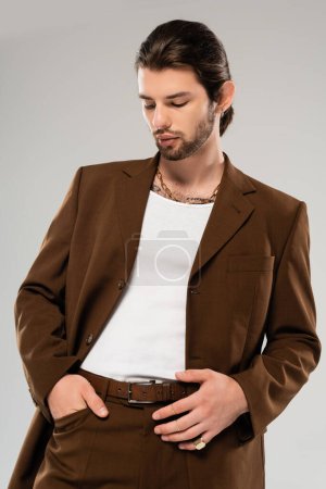 Stylish man in brown suit posing isolated on grey 