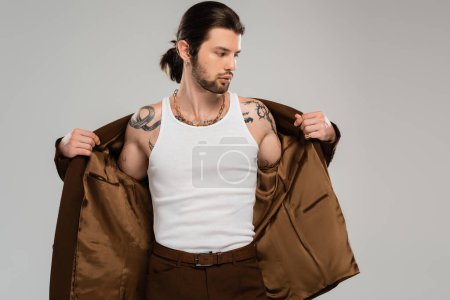 Long haired tattooed man wearing jacket isolated on grey 