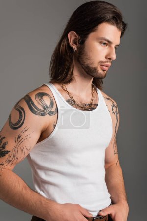 Long haired man with tattoo on body posing isolated on grey 