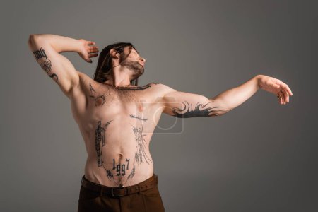 Foto de Muscular and tattooed model posing isolated on grey - Imagen libre de derechos