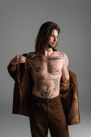 Stylish tattooed man wearing blazer isolated on grey 