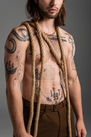 Cropped view of bearded and tattooed man with rope isolated on grey 