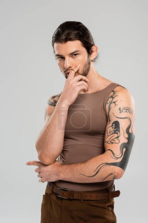 Young tattooed model in tank top posing isolated on grey 