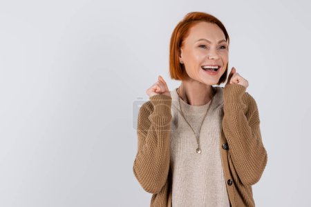 Fröhliche rothaarige Frau zeigt Ja-Geste isoliert auf grau 