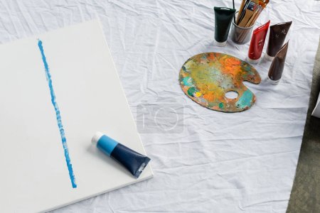 Draufsicht auf Farbtuben und Malerei auf Tuch im Atelier 