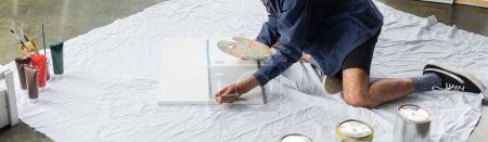 Téléchargez les photos : Cropped view of african american artist painting on canvas in workshop, banner - en image libre de droit
