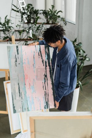 Young african american artist looking at drawing in studio 