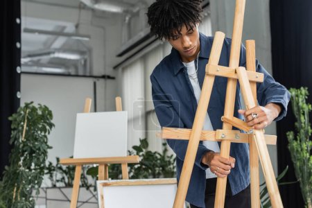 Jeune artiste afro-américain réglementant le chevalet en studio  
