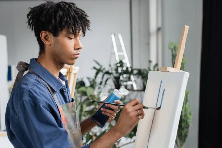 Afroamerikanischer Künstler in Schürzenmalerei auf weißer Leinwand im Atelier 