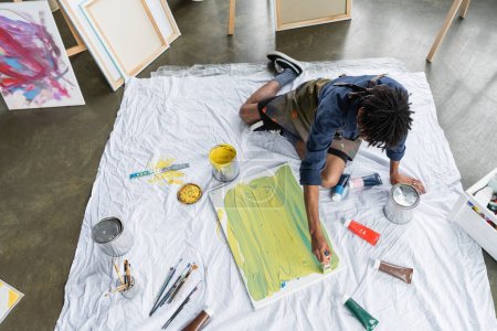 Vista aérea de la pintura de artista afroamericano sobre lienzo en el suelo en el estudio de arte 