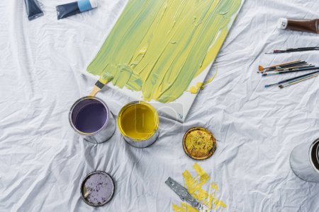 Téléchargez les photos : Top view of paints in jars and canvas on cloth in studio - en image libre de droit