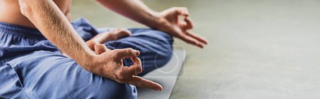 Photo for Cropped view of man in blue pants sitting in lotus pose and doing gyan mudra, banner - Royalty Free Image