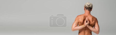 Photo for Back view of shirtless man doing anjali mudra behind back on grey background, banner - Royalty Free Image