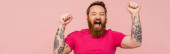 excited tattooed man with closed eyes shouting and showing win gesture isolated on pink, banner Longsleeve T-shirt #639506178