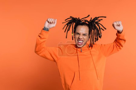 Téléchargez les photos : Excited multiracial man with tattoo celebrating on coral background - en image libre de droit