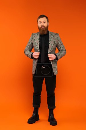 Photo for Full length of stylish man adjusting jacket on red background - Royalty Free Image