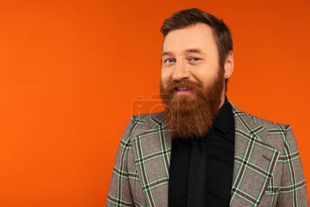 Photo for Cheerful bearded man in checkered jacket and shirt looking at camera isolated on red - Royalty Free Image