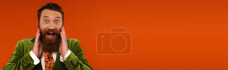 Photo for Astonished bearded man in velvet jacket looking at camera isolated on red, banner - Royalty Free Image