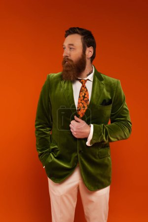 Tattooed and bearded man in green jacket looking away isolated on red 