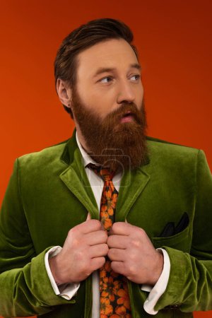 Photo for Trendy bearded man in velvet jacket looking away isolated on red - Royalty Free Image