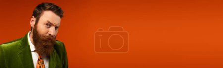 Photo for Focused and breaded man looking at camera on red background, banner - Royalty Free Image