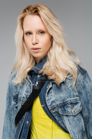 young blonde model with blue eyes looking at camera isolated on grey 