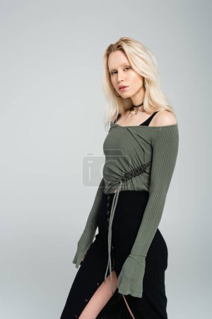 Téléchargez les photos : Femme blonde en chemise à manches longues et jupe noire regardant la caméra isolée sur gris - en image libre de droit