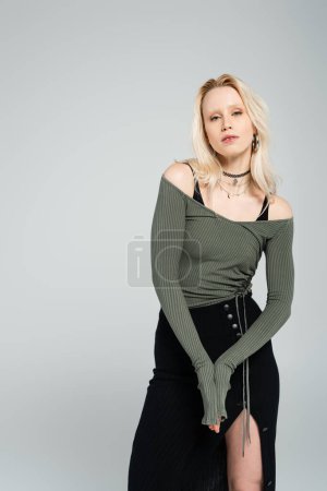 Téléchargez les photos : Femme blonde en chemise à manches longues et jupe noire debout isolée sur gris - en image libre de droit