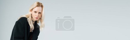 Téléchargez les photos : Femme blonde en tenue noire posant tout en regardant la caméra isolée sur gris, bannière - en image libre de droit