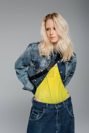 Photo for Blonde albino woman in blue denim outfit posing isolated on grey - Royalty Free Image