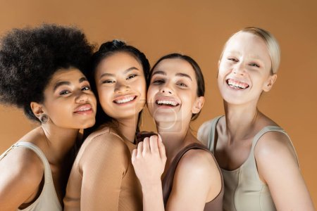 modelos multiétnicos excitados en ropa interior sonriendo a la cámara aislada en beige