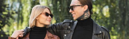 Photo for Happy tattooed man in sunglasses hugging girlfriend in leather jacket, banner - Royalty Free Image