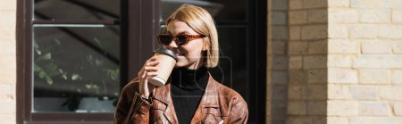 happy blonde woman in sunglasses and leather jacket drinking coffee outdoors, banner 