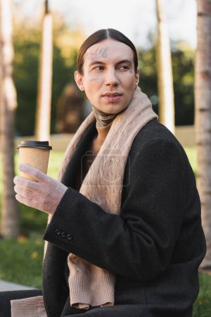 stylish man in coat and scarf holding paper cup with coffee to go 
