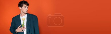 Photo for Curly man holding tulip behind jacket on red background, banner - Royalty Free Image