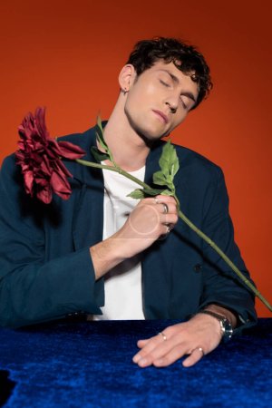 Foto de Hombre de moda en chaqueta azul con flores de dalia aisladas en rojo - Imagen libre de derechos