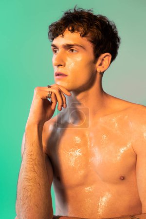 Shirtless man with oil on body looking away on green background 