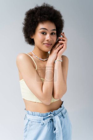 Pretty african american woman in top looking at camera isolated on grey 