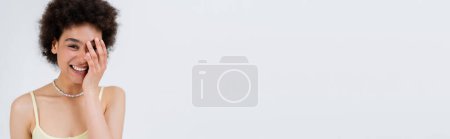 Photo for Young african american woman touching face isolated on grey, banner - Royalty Free Image