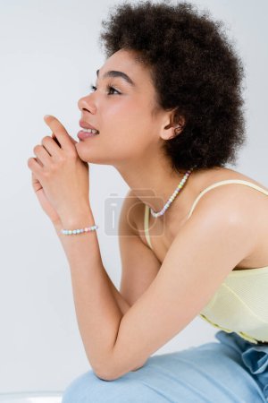 Positive african american woman in top looking away isolated on grey 
