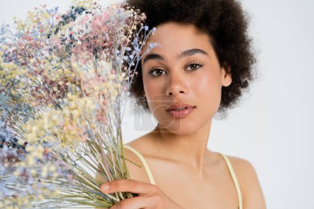 Young african american model posing with baby breath flowers isolated on grey 