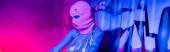 anonymous tattooed woman in balaclava near wall with graffiti in blue and pink lighting with smoke, banner puzzle #645514460