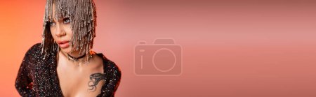 Foto de Retrato de mujer sexy en peluca metálica con diamantes de imitación brillantes mirando hacia otro lado sobre fondo rosa y naranja, bandera - Imagen libre de derechos