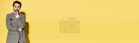 Téléchargez les photos : Homme à la mode en veste à carreaux regardant la caméra sur fond jaune, bannière - en image libre de droit